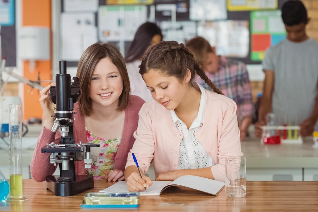 Zwei Schülerinnen mit Mikroskop im Klassenzimmer